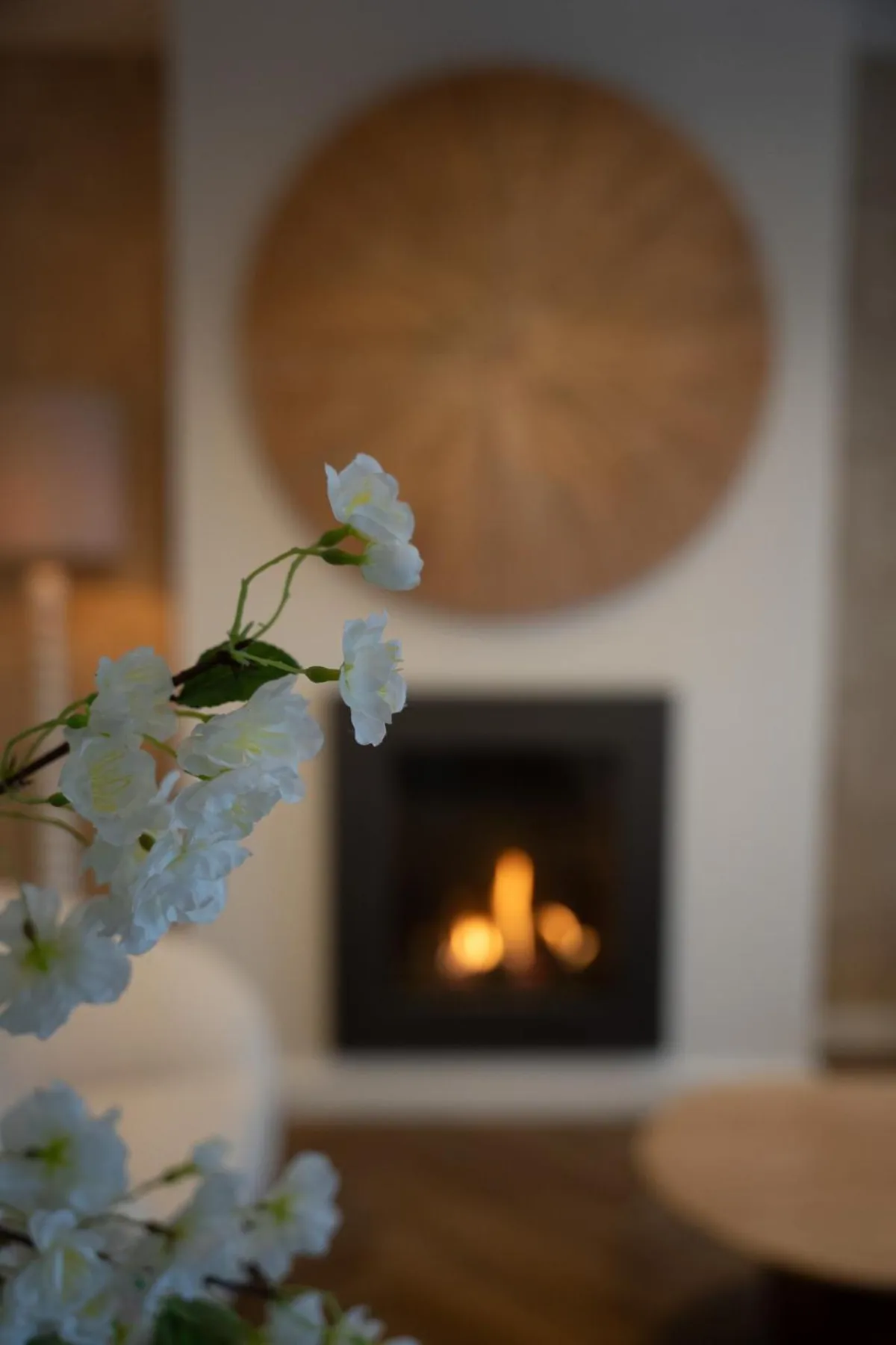 Brandende haard en gevlochten wandschijf in de Deluxe Suite, witte bloesem op de voorgrond