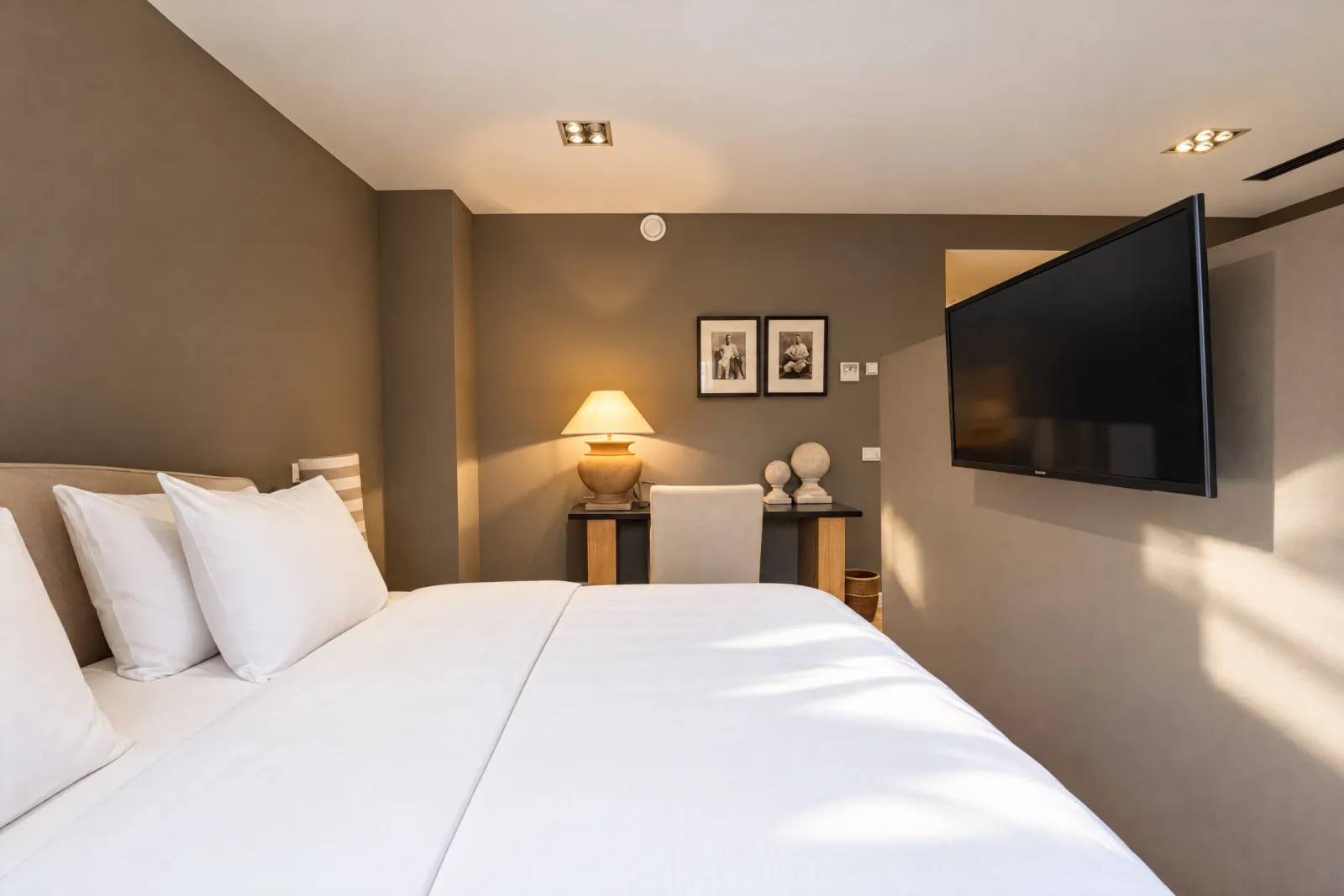 Opgemaakt bed met wit linnen en een televisie aan de wand in de Mystery Suite