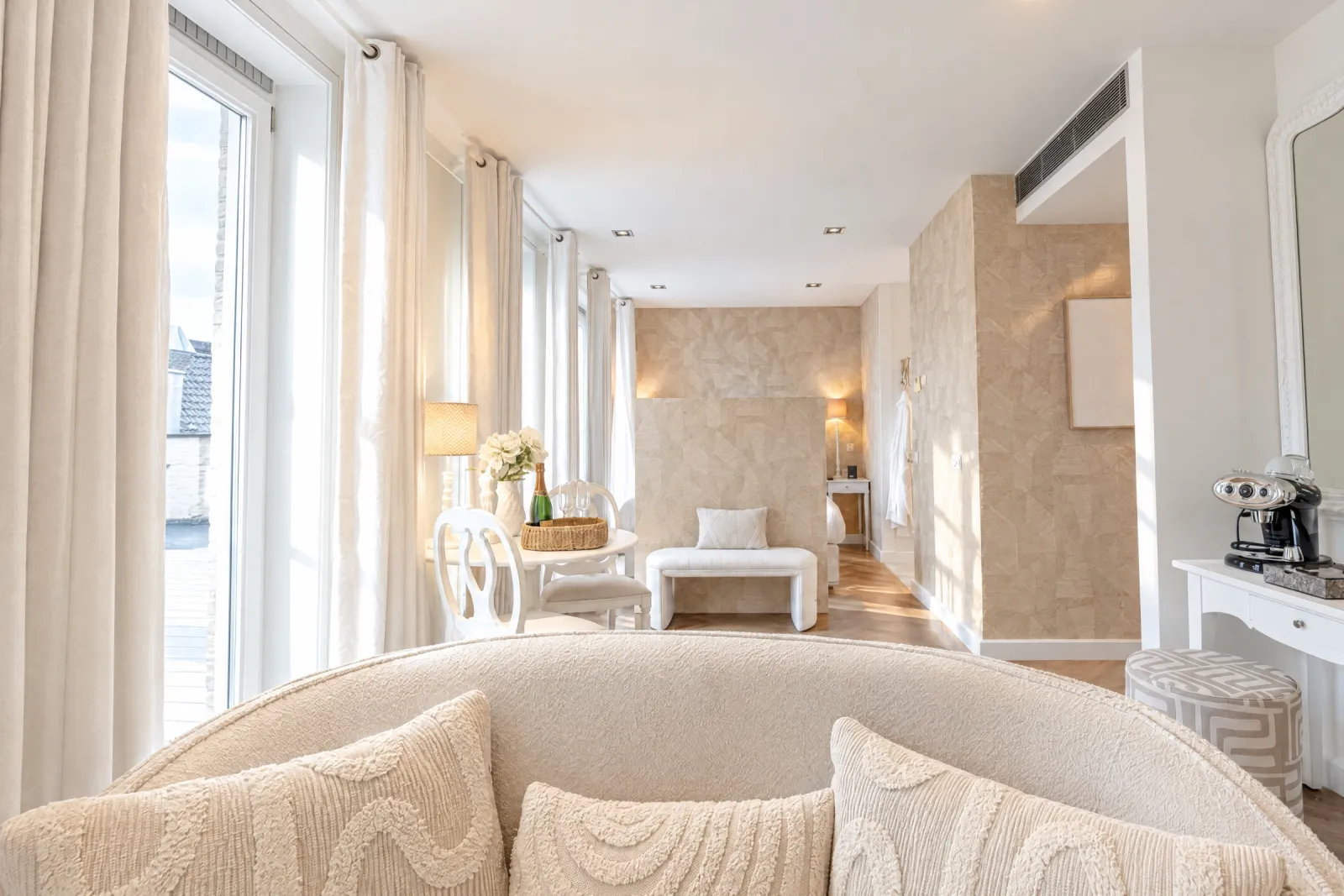 Doorkijk door de Deluxe Suite van de zithoek naar het bed en de deuren naar het balkon
