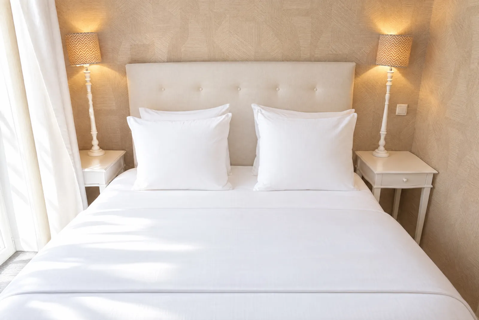 Opgemaakt bed met crème capitonné hoofdbord en lampjes in de Deluxe Suite