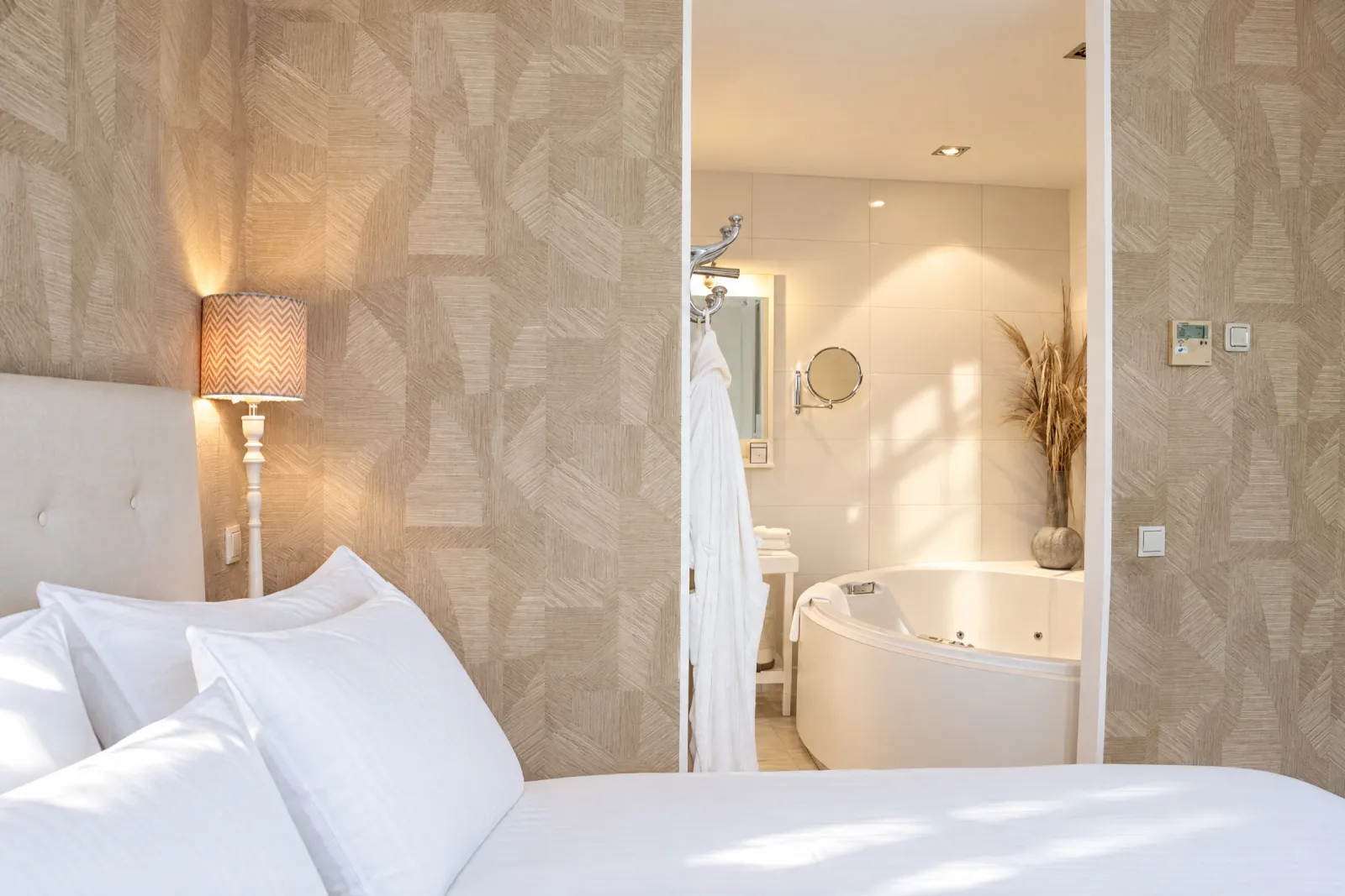 Vanaf het bed zicht op de open badkamer met jacuzzi in de Deluxe Suite