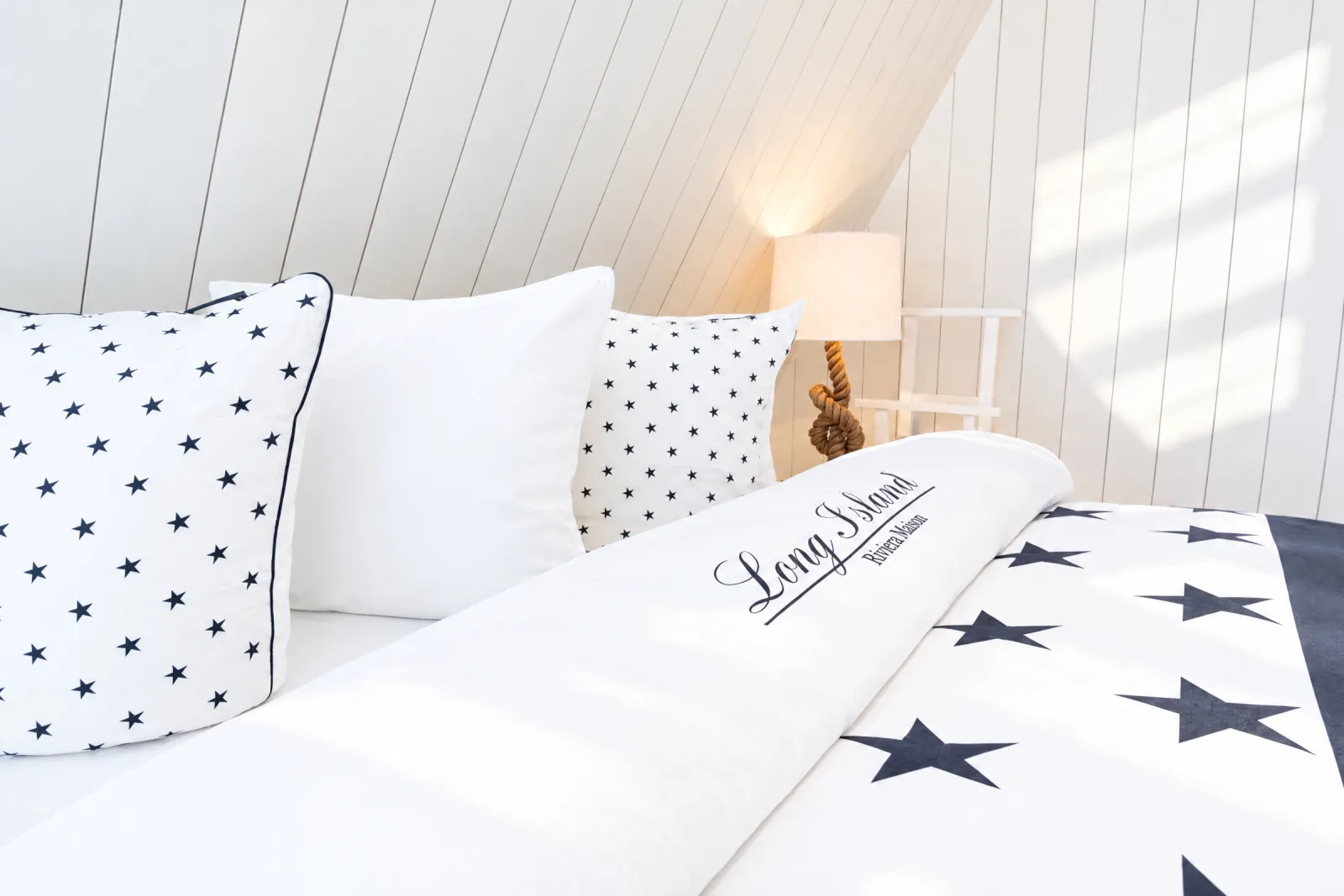 Bed met sterrendekbed onder het witte schuine plafond van de Hamptons Suite