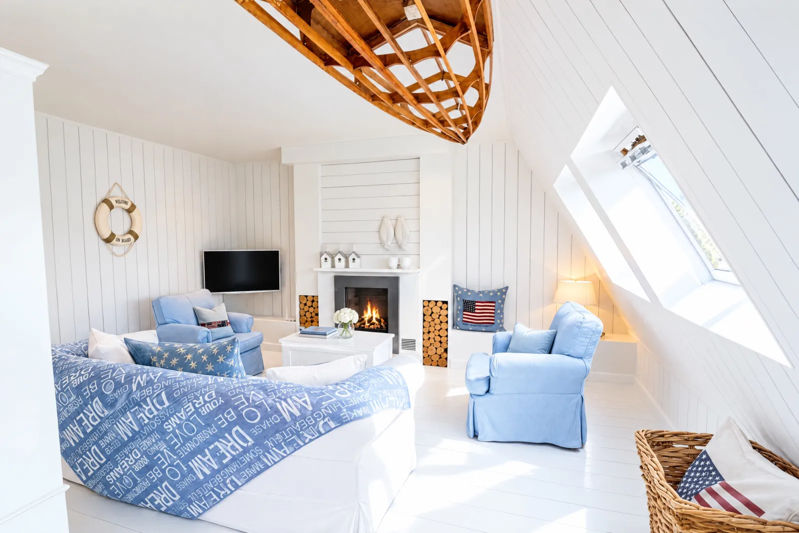 Witte zithoek met lichtblauwe fauteuils en haard onder het schuine dak van de Hamptons Suite