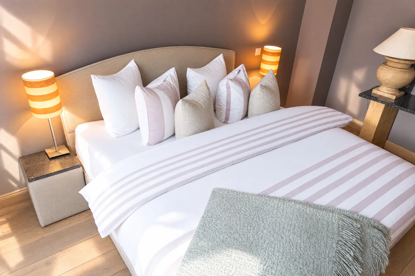 Bed met gestreept dekbed, veel kussens en gestreepte lampjes in de Black & White Suite